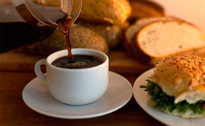 Sirviendo taza de café con diferentes bollos